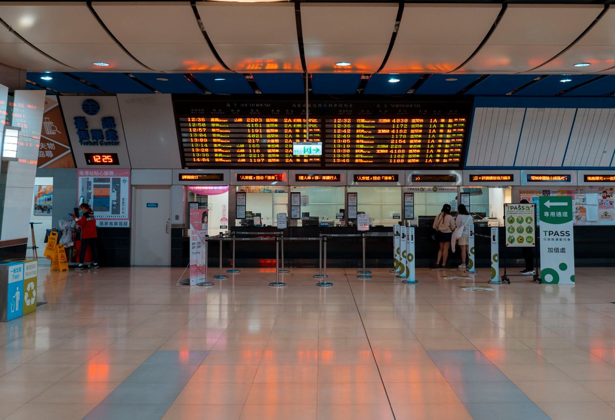 A China Railway high-speed train at a busy departures hall with an electronic timetable board