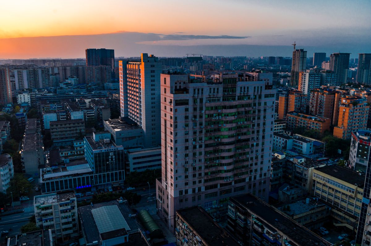 Chengdu's skyline at dusk, with residential towers lit against an orange sky