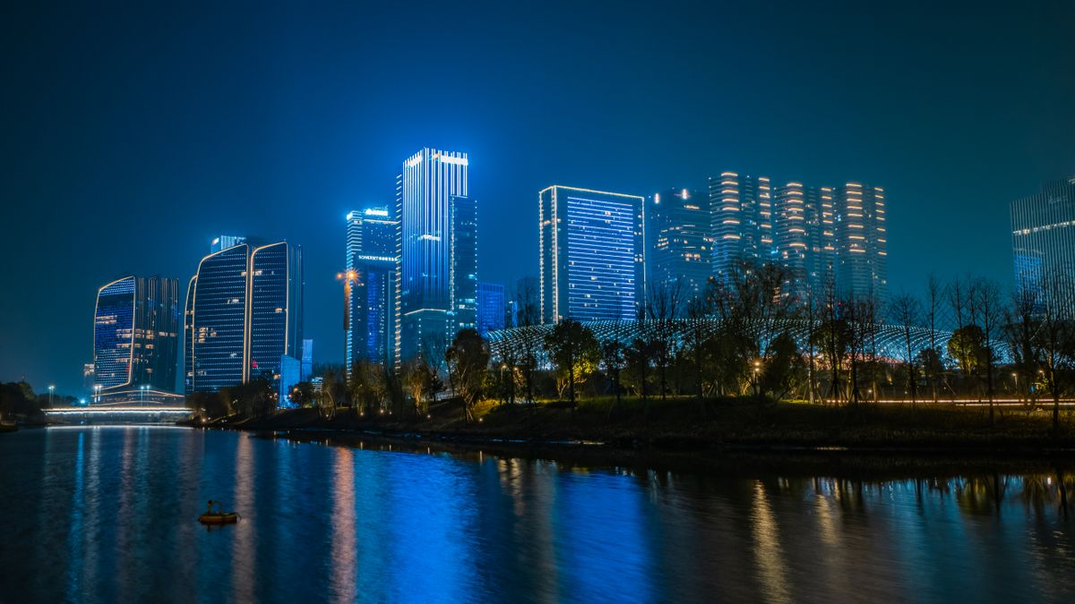 Hangzhou's skyline lit up at night, reflecting on the water near the city center