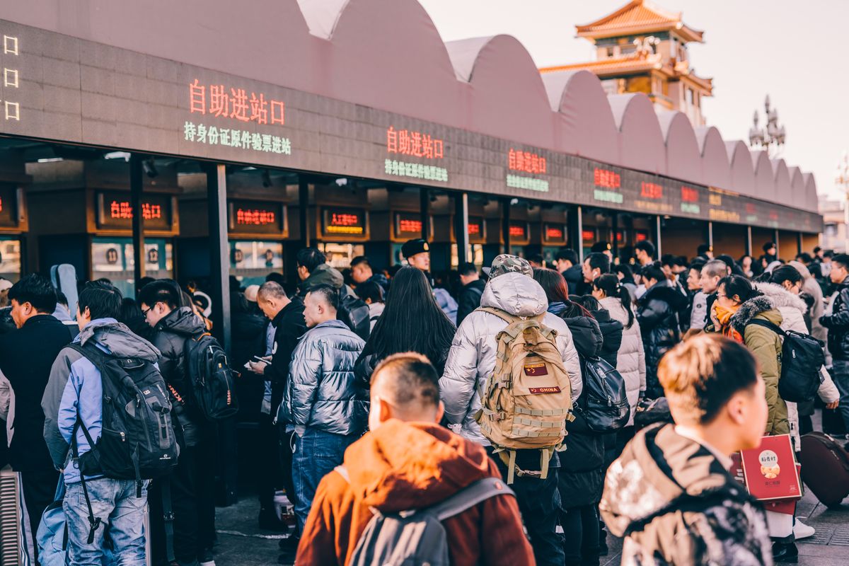 Passengers queue at self-service gates outside a busy Chinese railway station during peak travel season