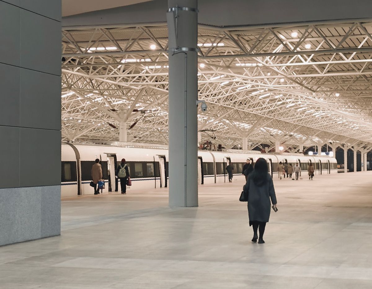 Passengers boarding a train at a modern Chinese railway station platform