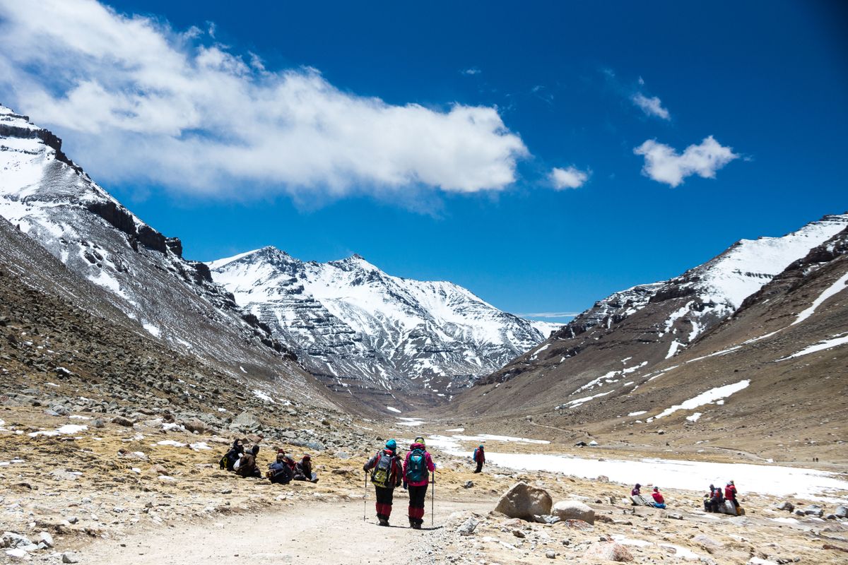 Excursionistas caminando por un valle de montaña tibetano de gran altitud con picos nevados