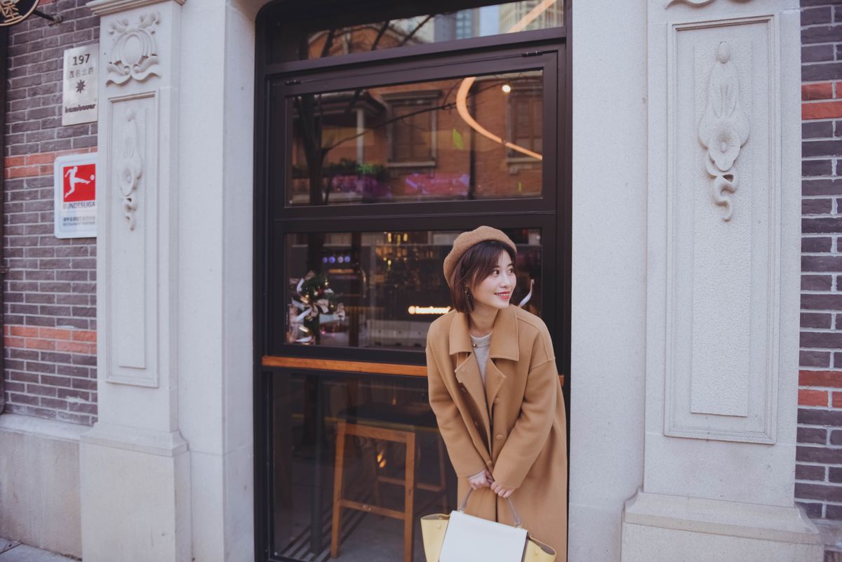 Woman in a coat standing outside a café storefront in a Chinese city