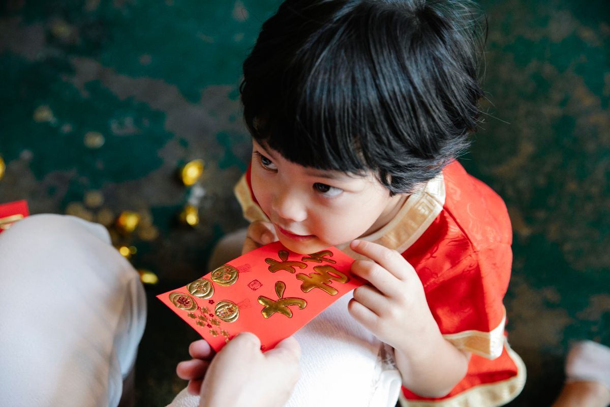 A child holds a red envelope decorated with gold characters during a Chinese New Year celebration