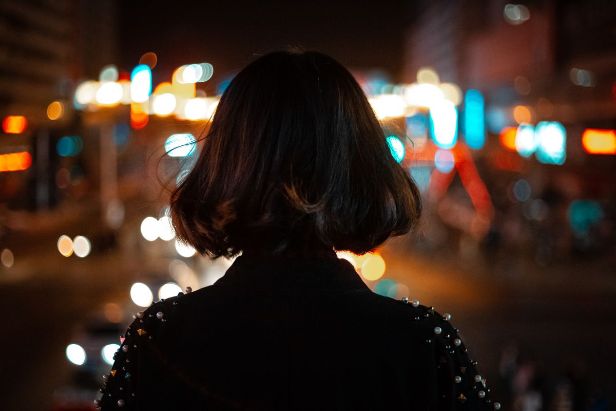Woman walking a busy neon-lit street at night in a Chinese city