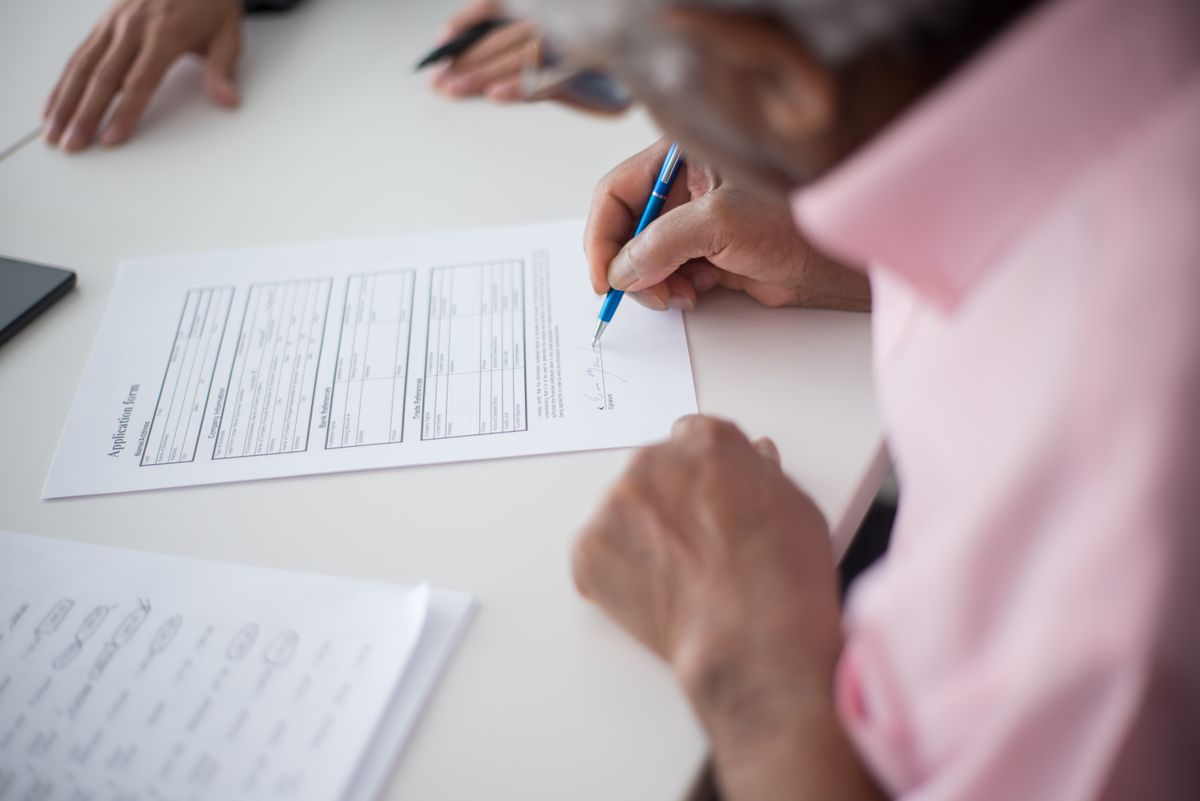 Mano firmando un formulario de solicitud de visa con bolígrafo