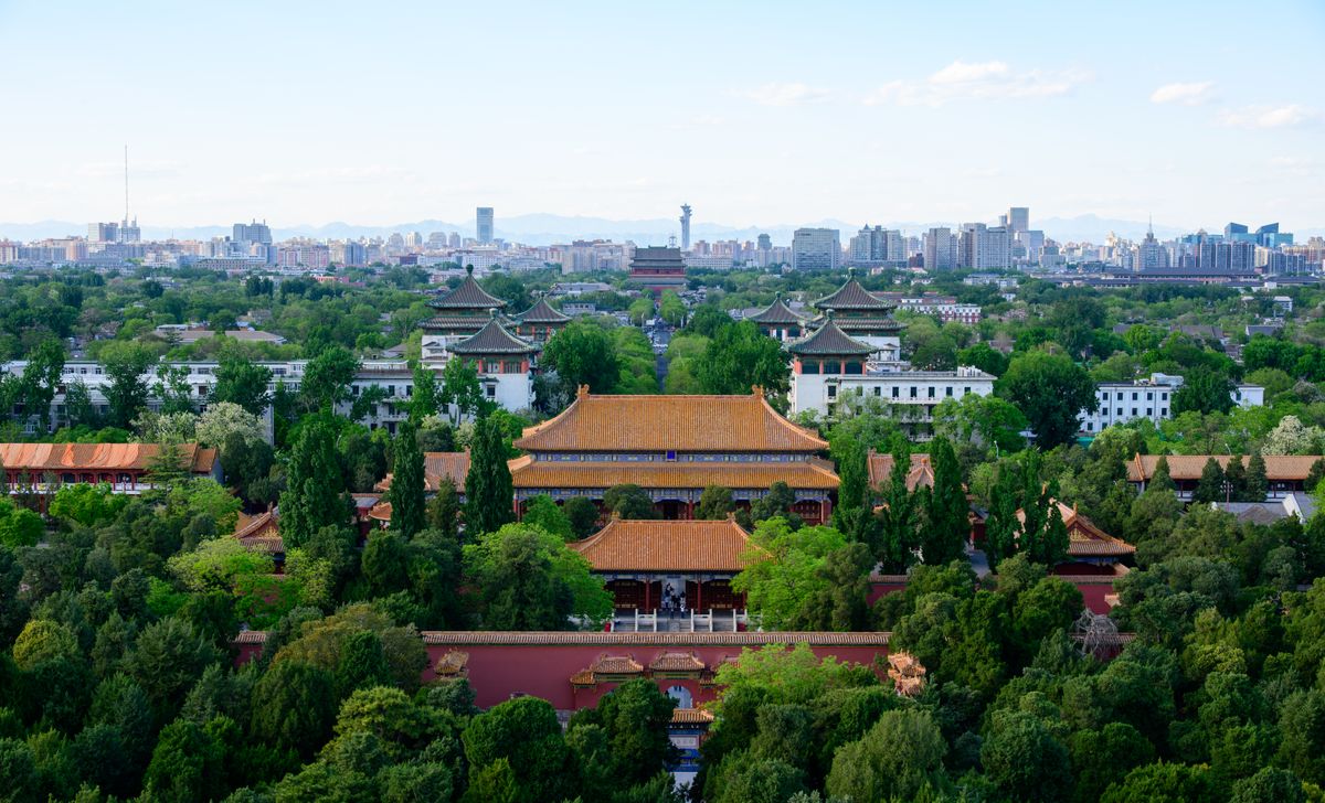 Aerial view of the Forbidden City and Beijing skyline surrounded by greenery