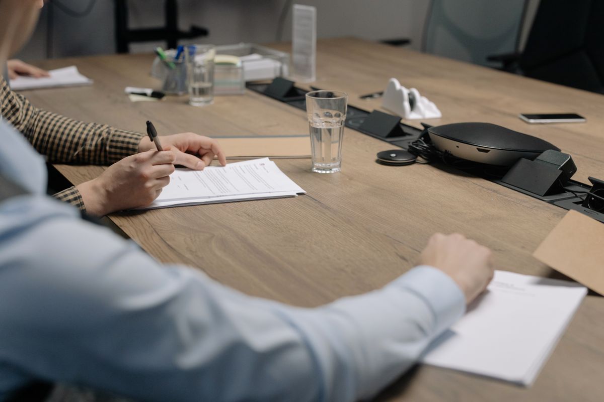 Two colleagues reviewing and signing a business document at an office table