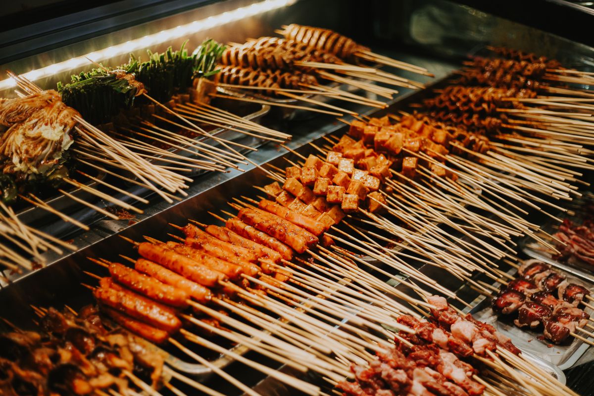 Una parrilla cargada de brochetas de comida callejera china