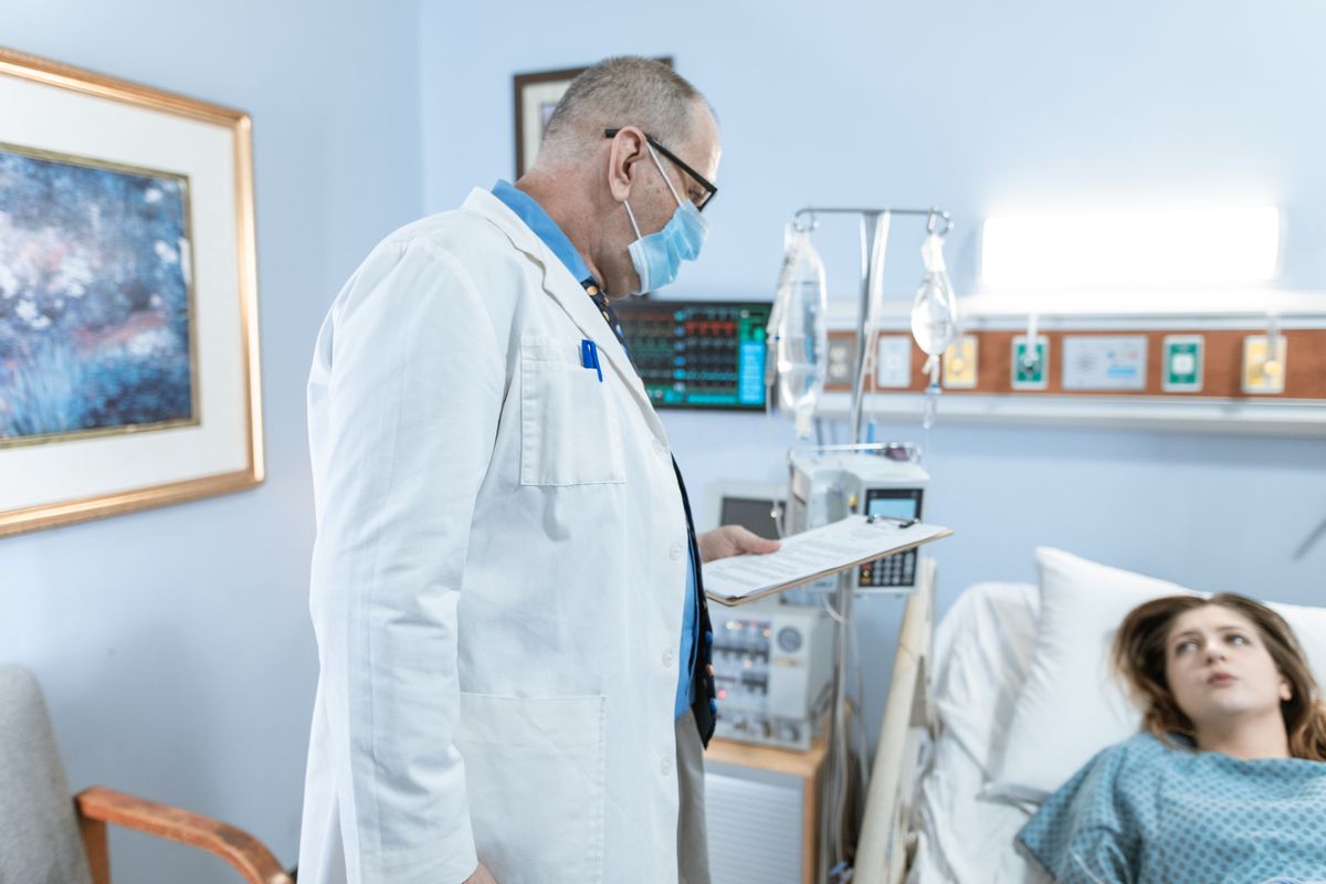 A doctor with a patient in a hospital room, where an international stay in China can top ¥150,000