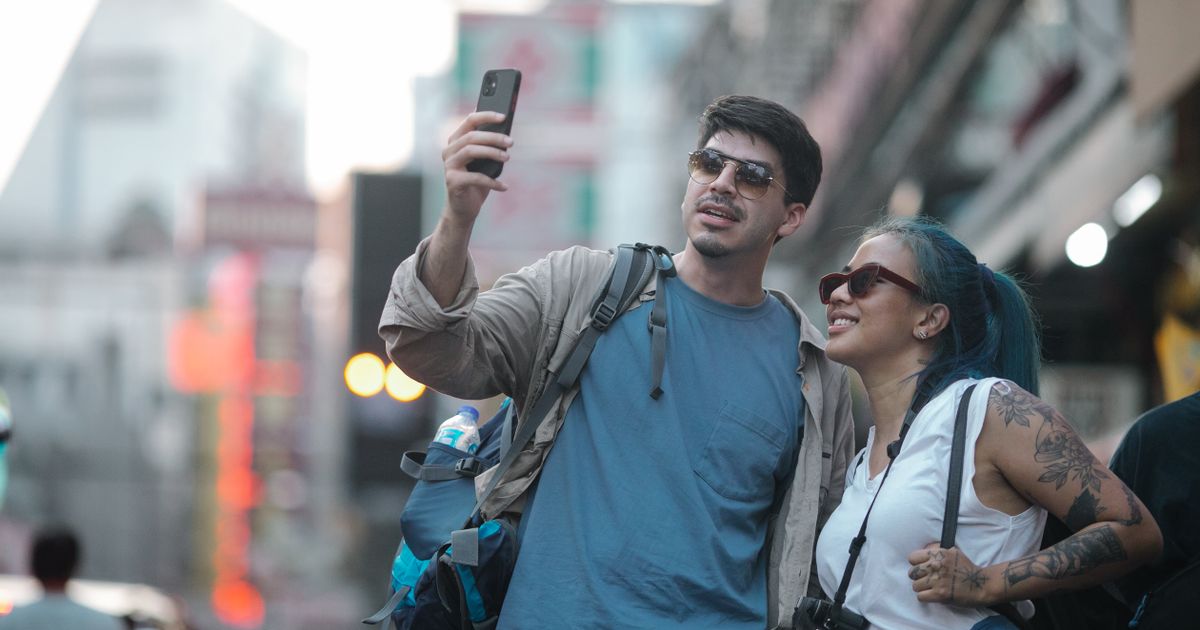 Two travelers checking a phone on a busy Chinese city street