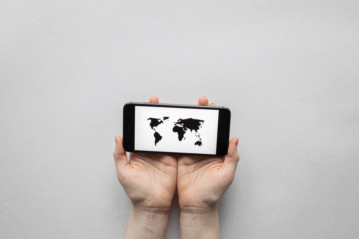 Hands holding a phone showing a world map, roaming data concept
