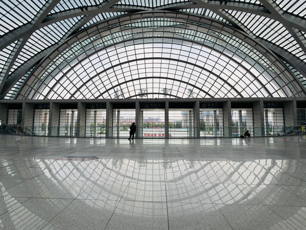 The bright, modern interior concourse of a large Chinese high-speed railway station