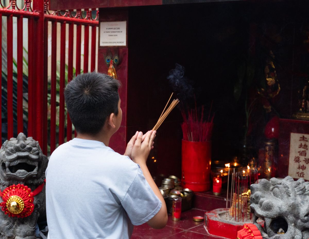 Young worshipper holding incense at a Chinese temple altar