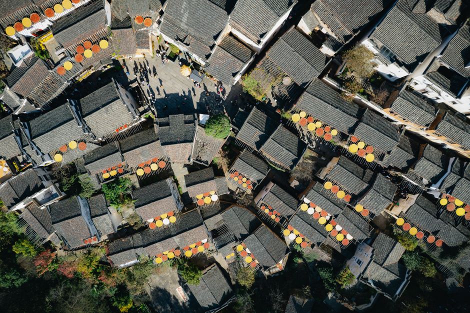 Stunning aerial shot of Chinese village rooftops with colorful drying racks in full sunlight.
