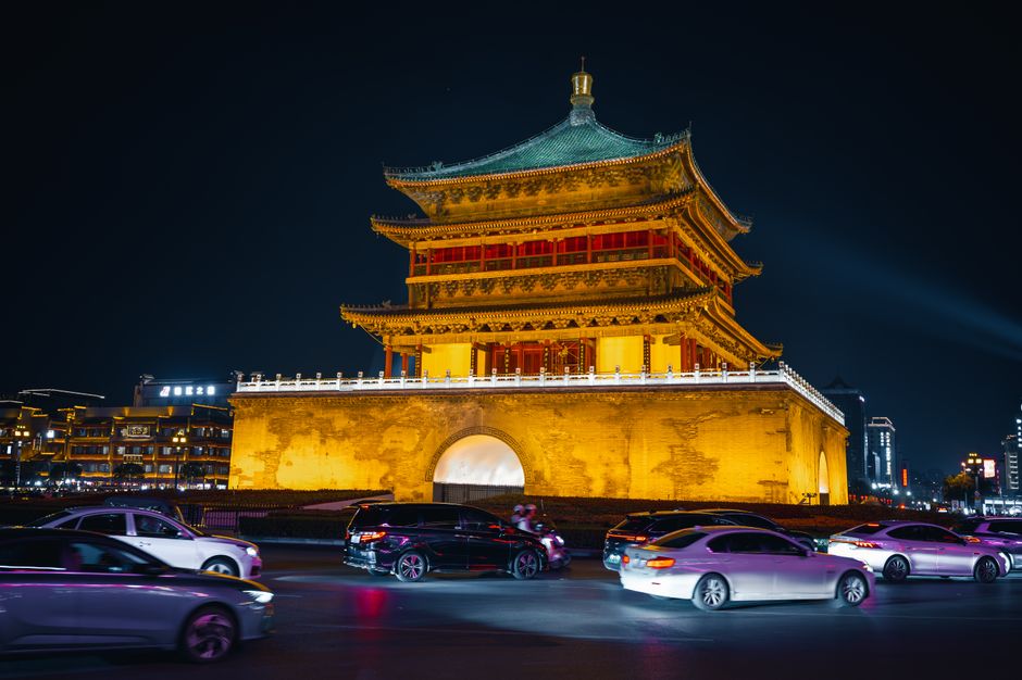 Vibrant night scene of Xi'an Bell Tower with traffic motion blur, beautifully illuminated.