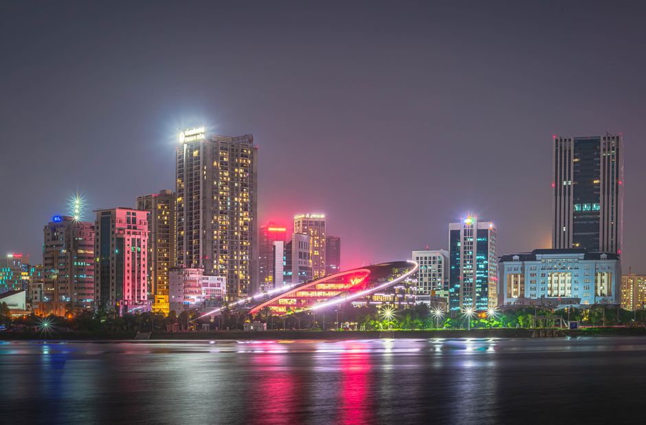 Dazzling city skyline at night with vibrant lights reflecting on water.