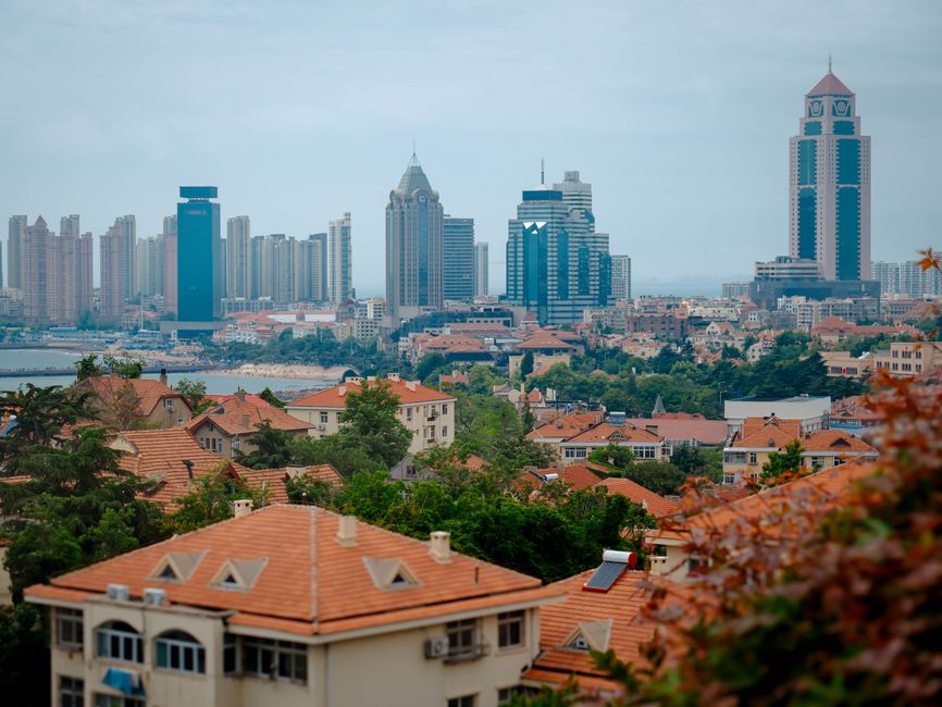 A scenic view of Qingdao's cityscape showcasing modern skyscrapers and traditional residential buildings.