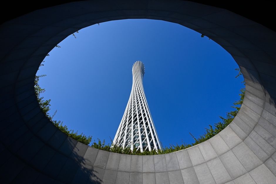 Canton Tower framed by a circular opening against a clear blue sky.