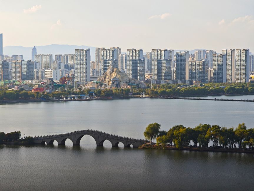 A beautiful urban skyline with a traditional bridge spanning across a lake.