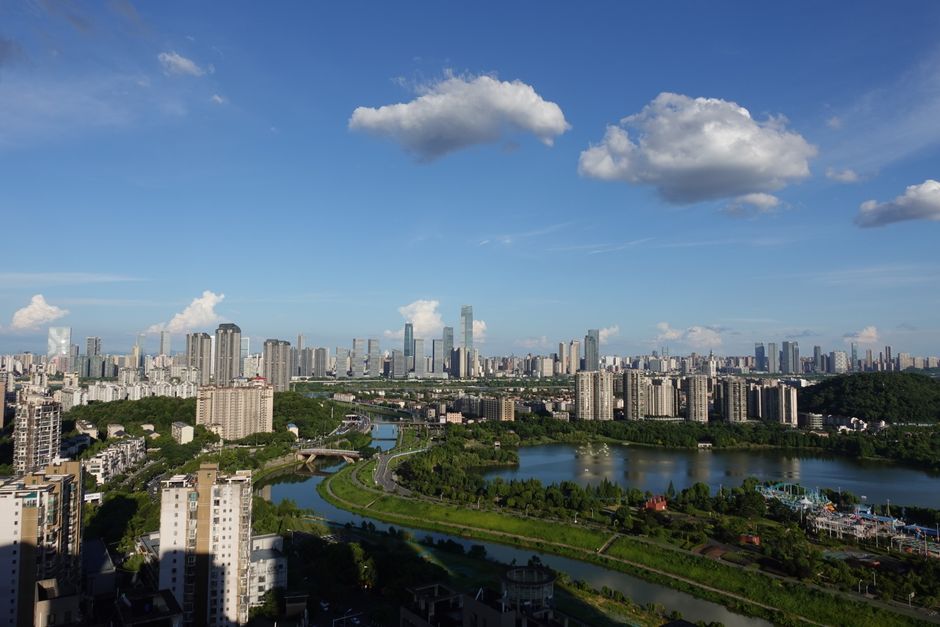 Breathtaking aerial view of a modern city skyline with a river and lush greenery under a clear blue sky.