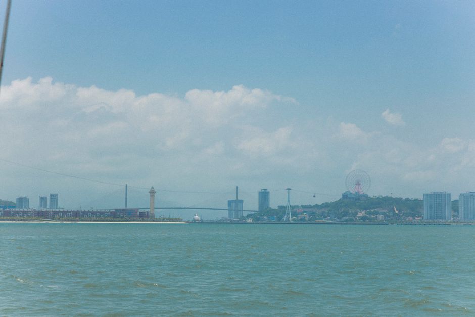 A vivid cityscape view with a lighthouse and ferris wheel beside a serene waterfront.
